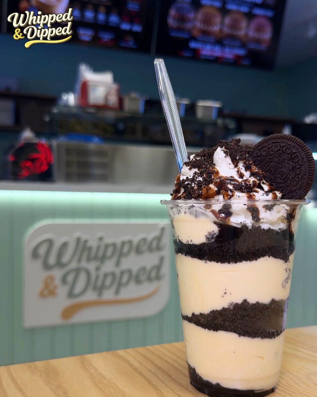 Oreo layered signature pudding topped with whipped cream and cookie crumbs